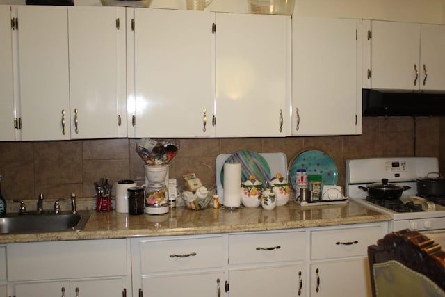 kitchen featuring white gas stove, a sink, range hood, white cabinetry, and decorative backsplash