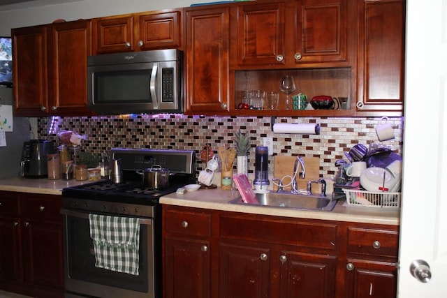 kitchen featuring a sink, open shelves, stainless steel appliances, light countertops, and decorative backsplash