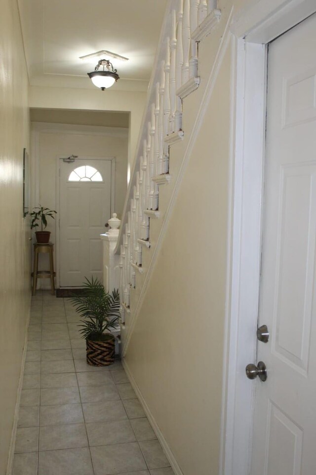 interior space with light tile patterned floors, baseboards, stairs, and crown molding