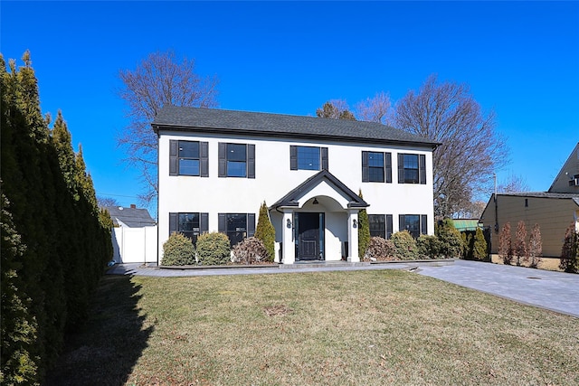 view of front of home with stucco siding, a front yard, and fence