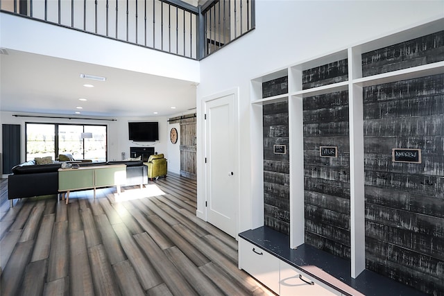 living room with recessed lighting, a barn door, a high ceiling, and wood finished floors