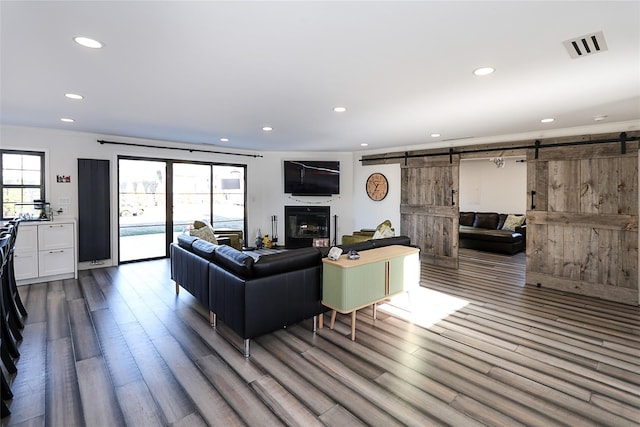 living room featuring plenty of natural light, recessed lighting, a barn door, and wood finished floors