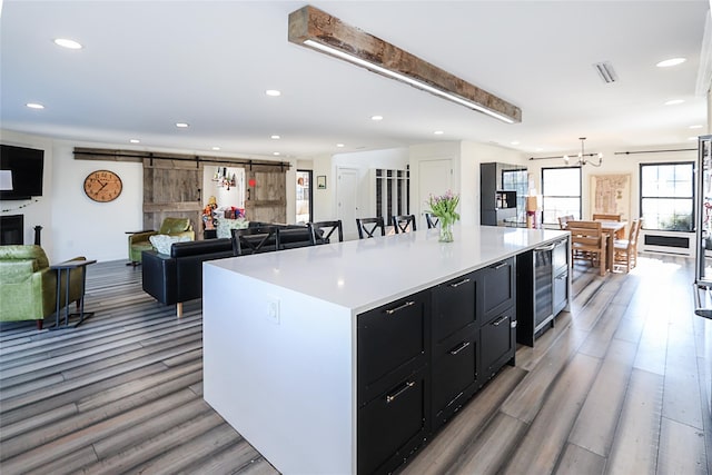 kitchen featuring a barn door, wood finished floors, dark cabinetry, and light countertops