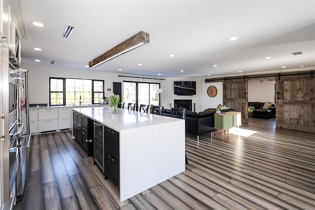 kitchen with visible vents, dark wood-type flooring, recessed lighting, a barn door, and white cabinets