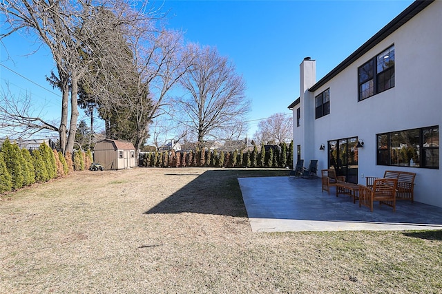 view of yard with a storage unit, a fenced backyard, an outdoor structure, and a patio