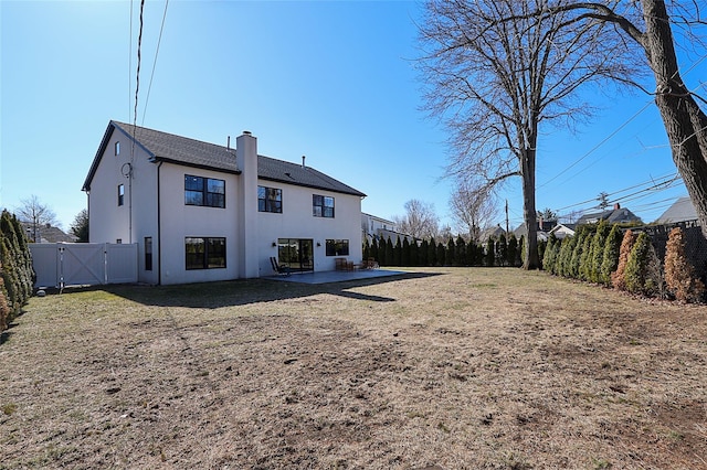 rear view of house with a patio, a gate, a fenced backyard, stucco siding, and a chimney