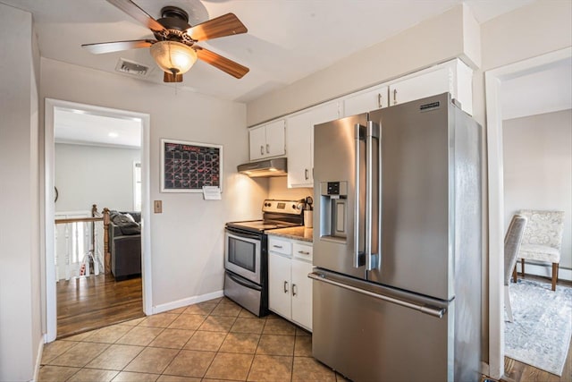 kitchen featuring light tile patterned floors, under cabinet range hood, stainless steel appliances, visible vents, and white cabinets