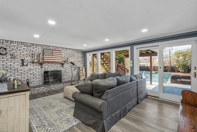 living room featuring a brick fireplace, brick wall, wood finished floors, and recessed lighting