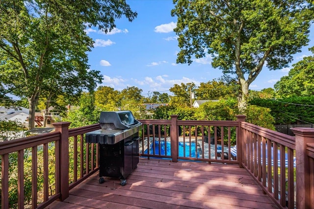 wooden deck with area for grilling and an outdoor pool