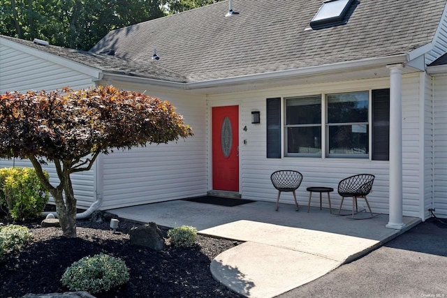 property entrance with a patio area and roof with shingles