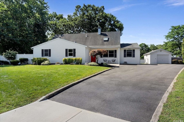 view of front of home featuring a detached garage, aphalt driveway, fence, an outdoor structure, and a front lawn