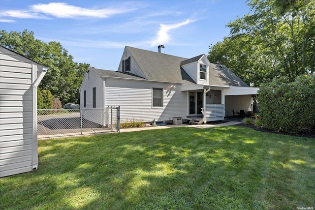 back of property with a yard, roof with shingles, and fence