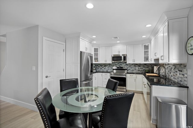 kitchen with stainless steel appliances, tasteful backsplash, visible vents, white cabinets, and a sink