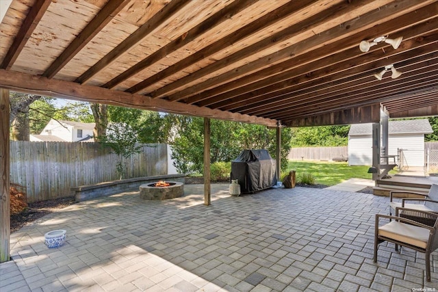 view of patio with a storage shed, a fire pit, a fenced backyard, a grill, and an outdoor structure