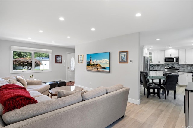 living room featuring recessed lighting, baseboards, and light wood finished floors