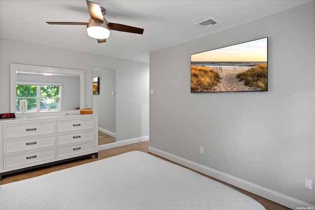 bedroom with ceiling fan, wood finished floors, visible vents, and baseboards