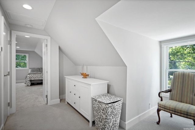 interior space featuring attic access, lofted ceiling, light carpet, and baseboards