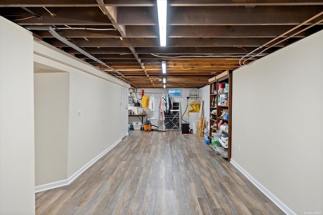 unfinished basement featuring baseboards and wood finished floors