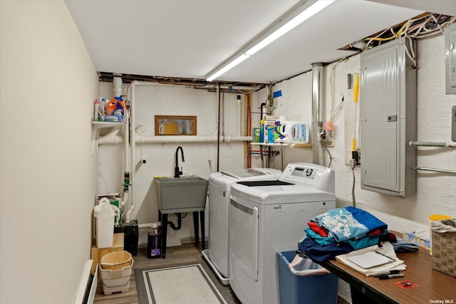 clothes washing area featuring washing machine and clothes dryer, a sink, wood finished floors, laundry area, and electric panel