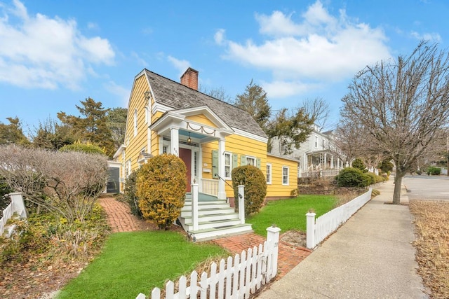 view of front of property featuring a fenced front yard, a chimney, a front lawn, and roof with shingles