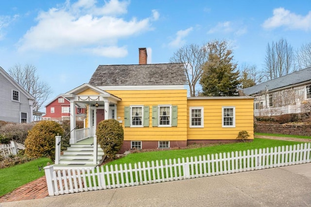 view of front of property with a shingled roof, a front yard, fence, and a chimney