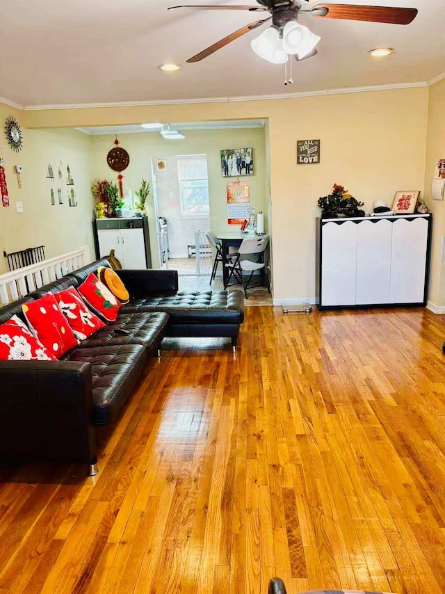 living area featuring ornamental molding, light wood-type flooring, ceiling fan, and baseboards