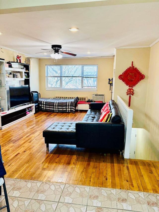 living area featuring ornamental molding, wood-type flooring, a wall mounted air conditioner, and a ceiling fan