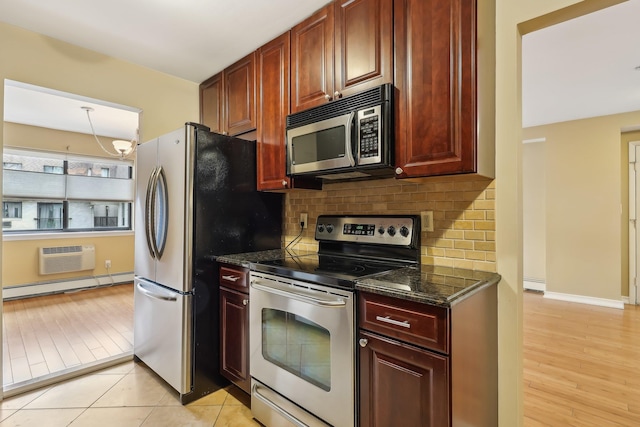 kitchen featuring backsplash, stainless steel appliances, reddish brown cabinets, dark stone counters, and a baseboard radiator