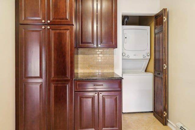 washroom featuring a baseboard heating unit, laundry area, light tile patterned flooring, and stacked washer and clothes dryer