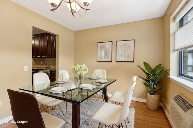 dining space with a notable chandelier, baseboards, light wood-type flooring, and a wall mounted air conditioner