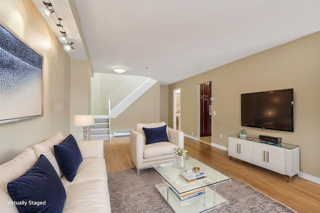 living area featuring stairway, wood finished floors, baseboards, and baseboard heating