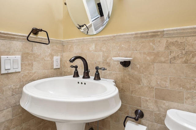 bathroom with wainscoting, tile walls, and a sink