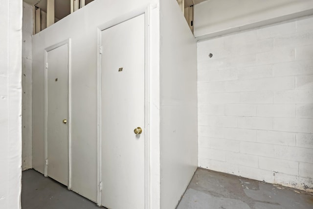 hallway with concrete block wall and unfinished concrete flooring