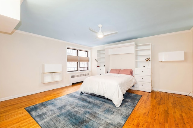 bedroom with crown molding, radiator heating unit, ceiling fan, wood finished floors, and baseboards