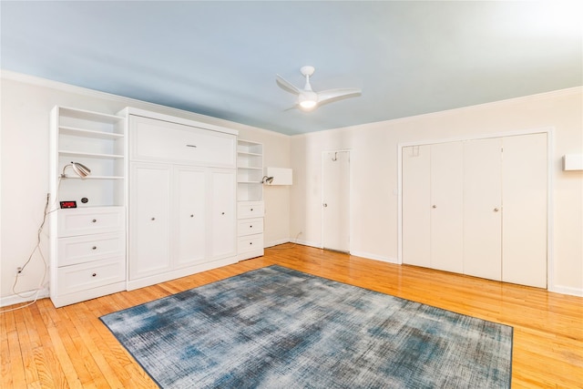 bedroom with light wood finished floors, baseboards, ceiling fan, crown molding, and two closets