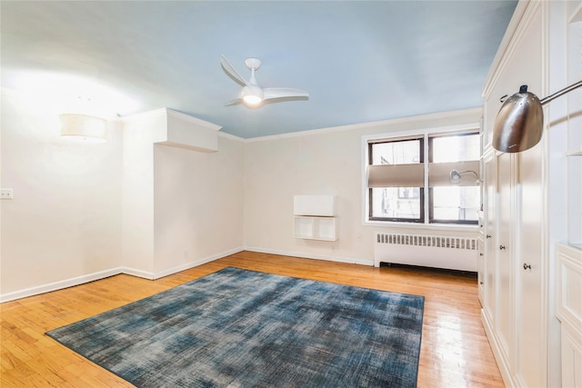 spare room with light wood-type flooring, radiator heating unit, baseboards, and crown molding