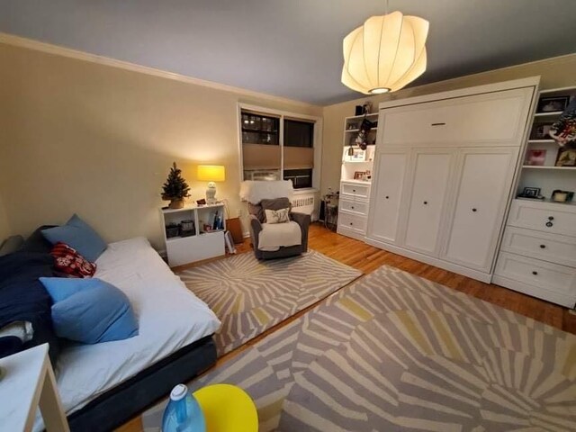 bedroom with ornamental molding and light wood-style flooring