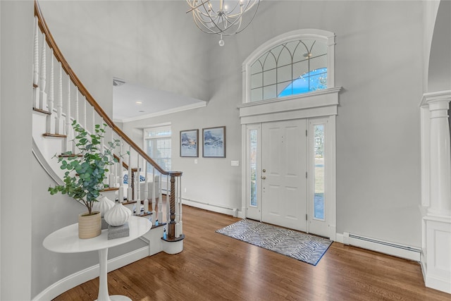 entryway with decorative columns, a baseboard heating unit, and wood finished floors