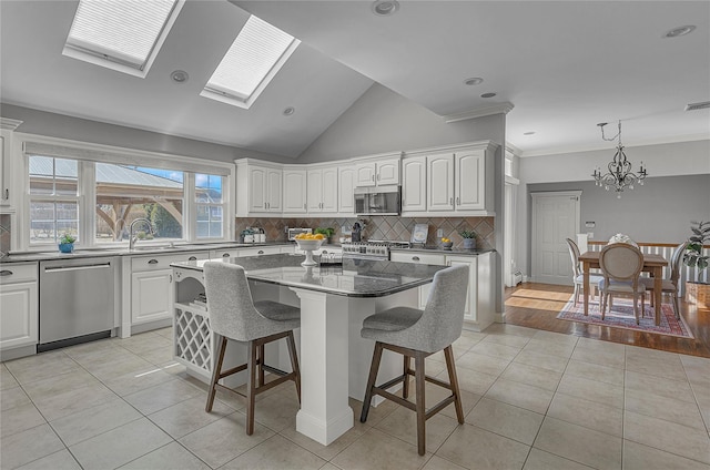 kitchen featuring light tile patterned floors, tasteful backsplash, a breakfast bar area, a center island, and stainless steel appliances