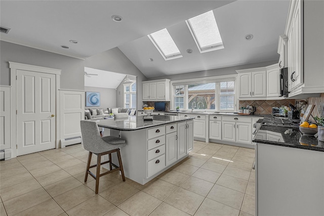 kitchen with a breakfast bar area, light tile patterned flooring, a kitchen island, and white cabinets