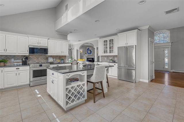 kitchen featuring light tile patterned floors, premium appliances, a breakfast bar, visible vents, and white cabinets