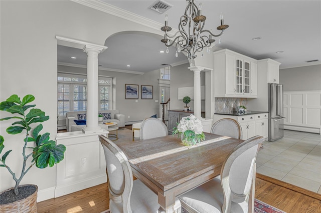 dining area with crown molding, light wood-style floors, visible vents, and decorative columns