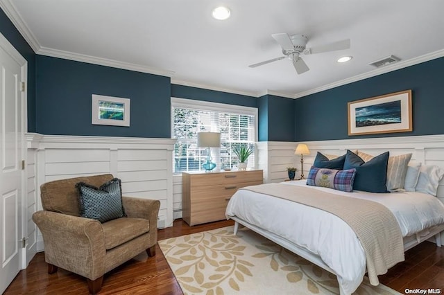 bedroom with a wainscoted wall, crown molding, visible vents, ceiling fan, and wood finished floors