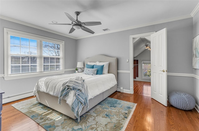 bedroom featuring a baseboard heating unit, visible vents, ornamental molding, and hardwood / wood-style flooring