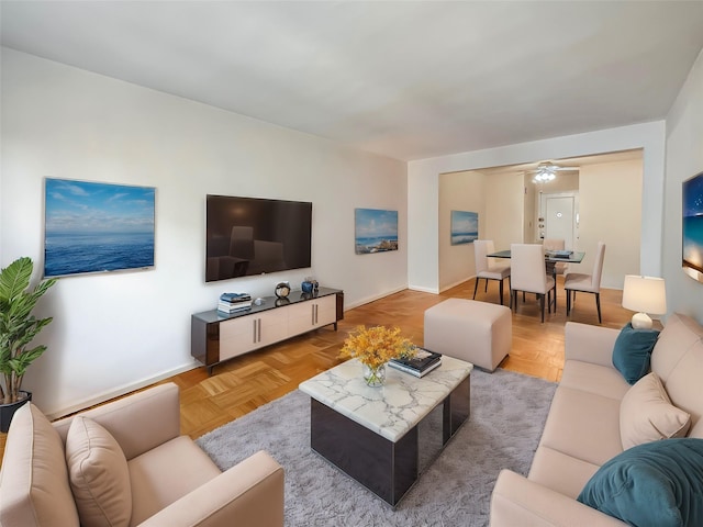 living area with a ceiling fan and baseboards