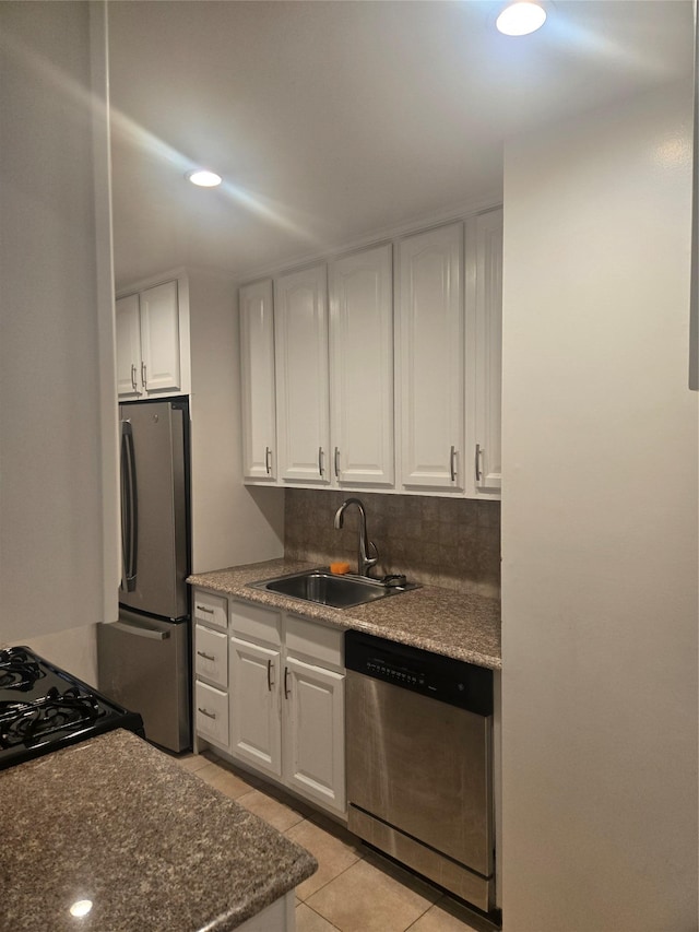 kitchen featuring light tile patterned flooring, a sink, white cabinets, appliances with stainless steel finishes, and backsplash