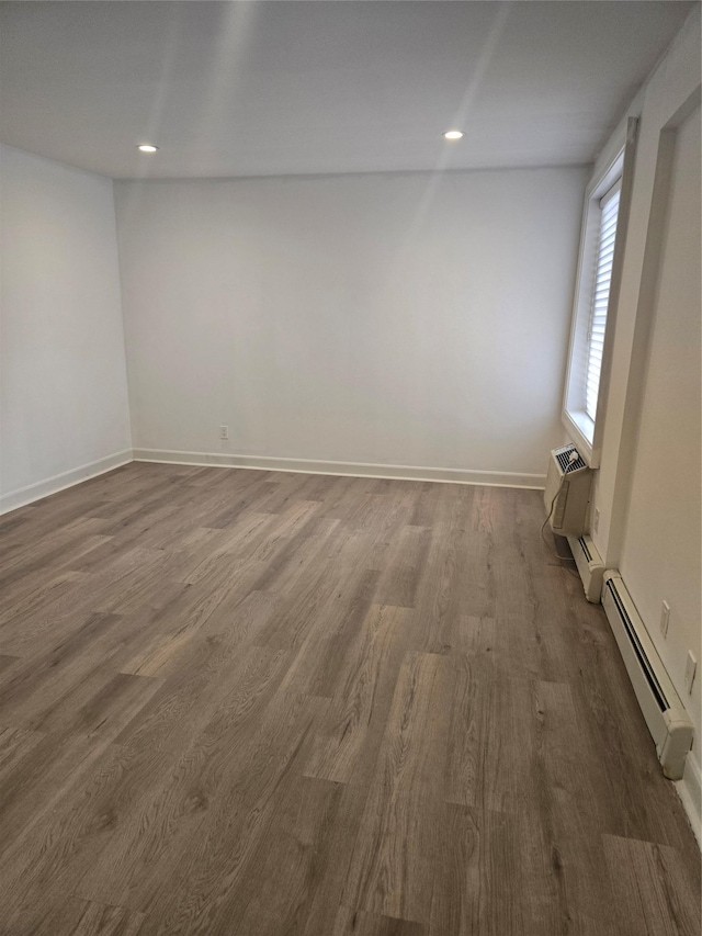 spare room with baseboard heating, recessed lighting, wood finished floors, and baseboards