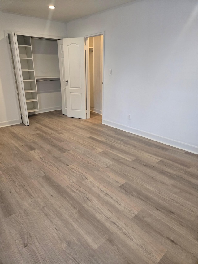 unfurnished bedroom featuring a closet, wood finished floors, and baseboards