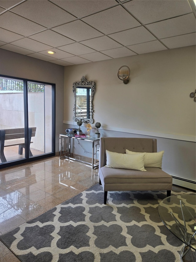 sitting room featuring a wealth of natural light, a baseboard radiator, baseboards, and a drop ceiling