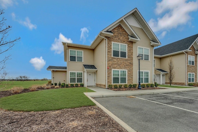 view of front of property with uncovered parking, a front yard, and stone siding